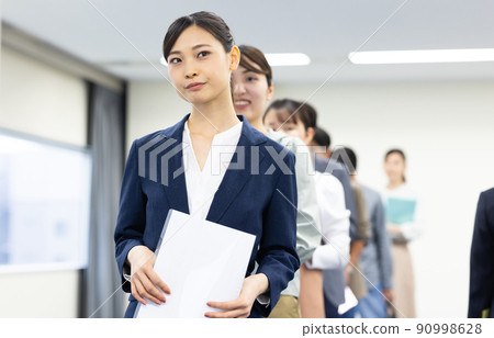 Men and women in a line waiting for their turn 90998628