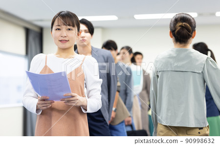 Men and women in a line waiting for their turn 90998632