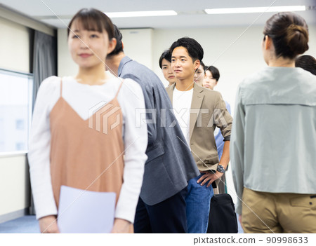 Men and women in a line waiting for their turn 90998633