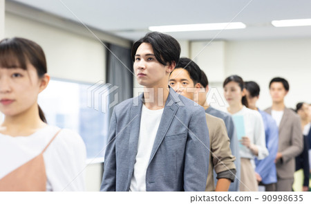 Men and women in a line waiting for their turn 90998635