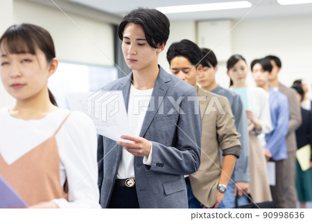 Men and women in a line waiting for their turn 90998636