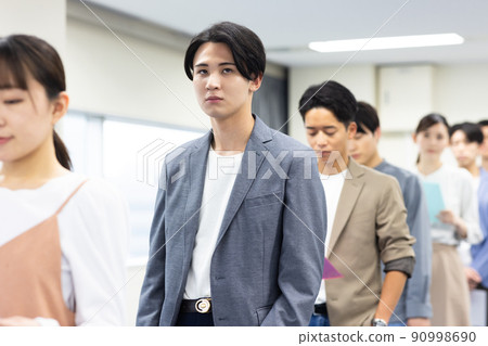 Men and women in a line waiting for their turn 90998690