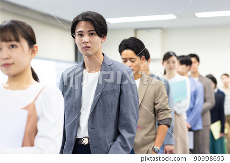 Men and women in a line waiting for their turn 90998693