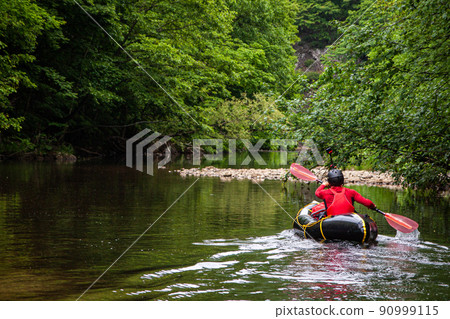 River rafting down a quiet mountain stream in Packraft 90999115