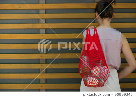 woman is holding mesh bag with products 90999345