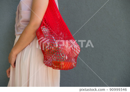 woman is holding mesh bag with products 90999346
