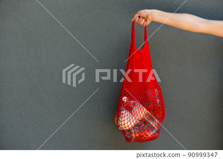 woman is holding mesh bag with products woman is holding mesh bag with products 90999347