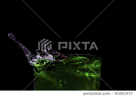 Water splashed from the mouth of the green glass. 91001457