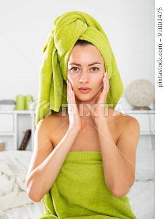 Girl in towel doing facial massage 91001476