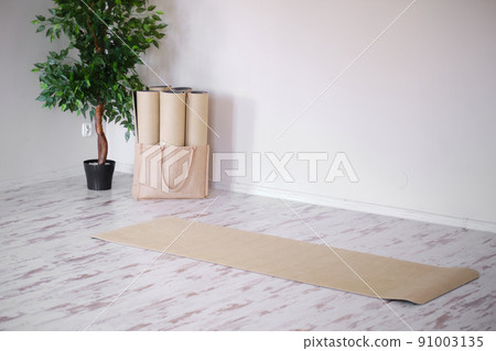 Unrolled yoga mat on wooden floor in modern fitness center or at home. 91003135