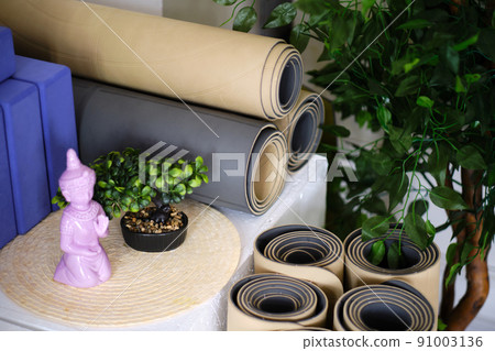 Several rolled rubber mats for yoga or fitness in beige and gray and foam blocks for sports in the studio. 91003136