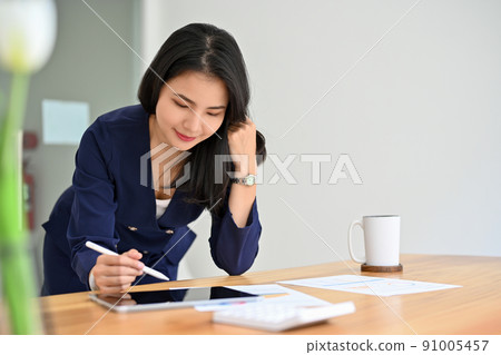 Gorgeous asian businesswoman leaning working on the table, reading a document 91005457