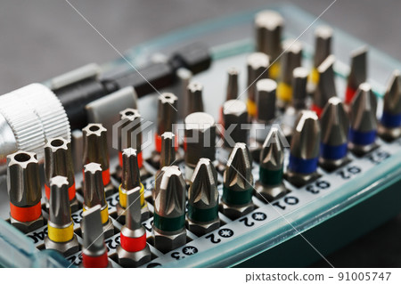 A set of different bits for screwdrivers and repairs in a box on a gray background A set of different bits for screwdrivers and repairs in a box on a gray background 91005747