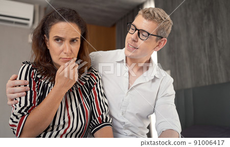 Husband consoles her tragic wife with depression in the bedroom, the wife and husband try to solve the difficult problems in life. Husband consoles her tragic wife with depression in the bedroom, the wife and husband try to solve the difficult problems in life. 91006417