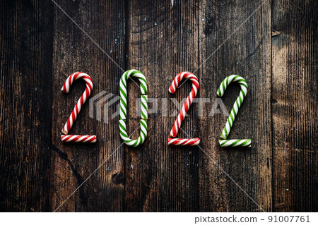 Year 2022 laid out from red, green and white striped candy canes on wooden background 91007761