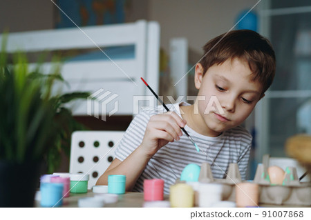 Cute little boy colouring eggs for easter 91007868