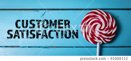 Customer Satisfaction. Text and red candy on a stick on a blue wooden background Customer Satisfaction. Text and red candy on a stick on a blue wooden background 91008112