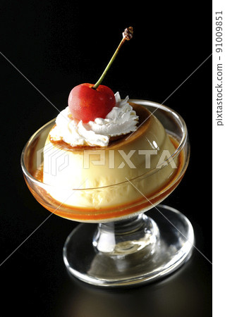 An old-fashioned retro pudding with cherries and cream on a sundae cup shot on a black background 91009851