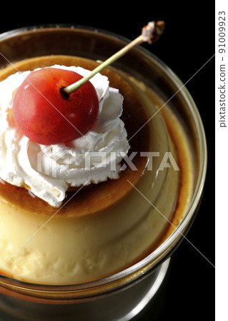 A bird's-eye view of the old-fashioned retro pudding with cherries and cream on the sundae cup on a black background 91009923