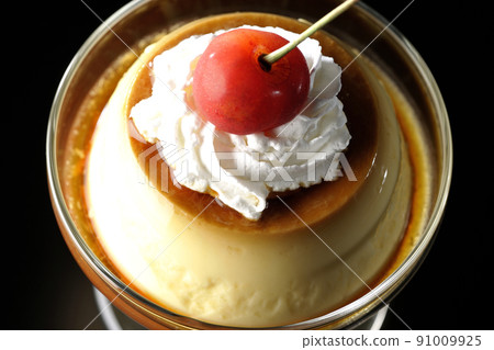 A bird's-eye view of the old-fashioned retro pudding with cherries and cream on the sundae cup on a black background 91009925