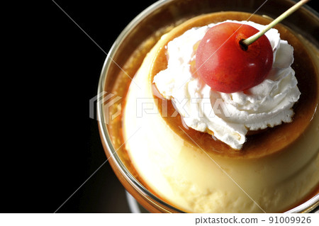 A bird's-eye view of the old-fashioned retro pudding with cherries and cream on the sundae cup on a black background 91009926