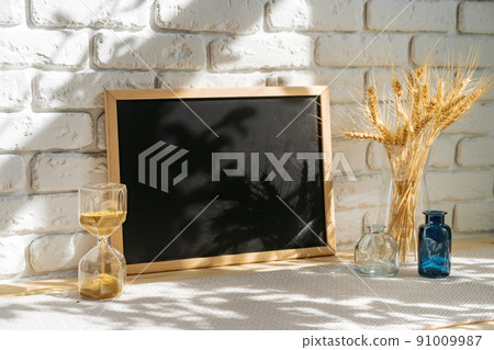 Photo frames on a brick wall background on the table with wheat ears in vase 91009987