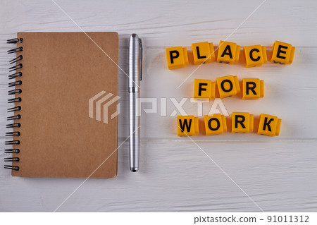 Notepad with brown cover and pen on white wood. 91011312
