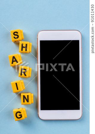 Smartphone and sharing word made of yellow cubes. 91011430