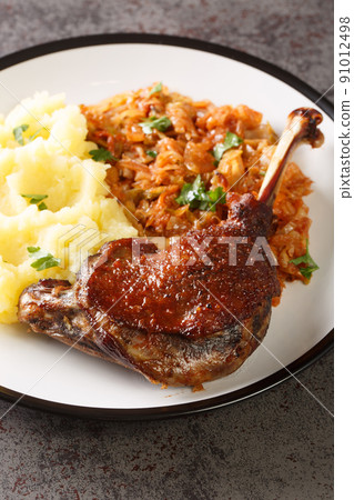Romanian Rata pe varza duck leg serving with mashed potatoes and stewed cabbage close-up in a plate. Vertical Romanian Rata pe varza duck leg serving with mashed potatoes and stewed cabbage close-up in a plate. Vertical 91012498
