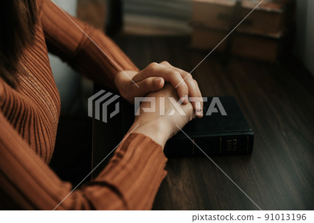 Hands together in prayer to God along with the bible In the Christian concept and religion, woman pray in the Bible on the table. Hands together in prayer to God along with the bible In the Christian concept and religion, woman pray in the Bible on the table. 91013196