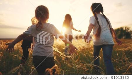 children run in the park at sunset. happy family kids camp kid dream concept. a group of children run on the grass at sunset the rays of the sun silhouette. childhood dream teamwork concept lifestyle 91013580