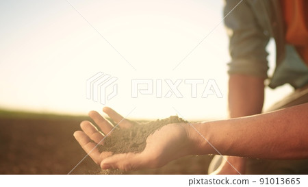 soil in the hands of the farmer. sun agriculture. close-up of a farmers hands holding black soil in their hands, fertile land. garden field ground fertile concept. worker holding soil plowed field soil in the hands of the farmer. sun agriculture. close-up of a farmers hands holding black soil in their hands, fertile land. garden field ground fertile concept. worker holding soil plowed field 91013665