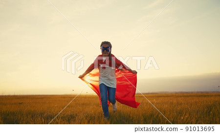 girl superhero. child in a red raincoat runs with a dog outdoors in the park. happy family kid dream concept. little girl superhero runs with a dog across the field lifestyle in nature 91013695