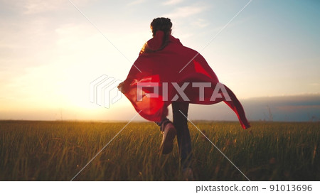 girl superhero. child in a red raincoat runs with a dog outdoors in the park. lifestyle happy family kid dream concept. little girl superhero runs with a dog across the field in nature 91013696