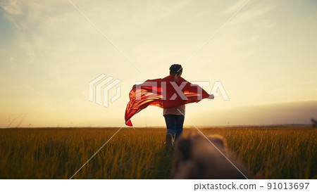 girl superhero. child in a red raincoat runs with a dog outdoors in the park. happy family kid lifestyle dream concept. little girl superhero runs with a dog across the field in nature 91013697
