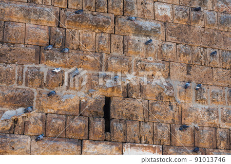 The ancient wall is paved with gray stones with doves. stone texture, outdoor stone tile The ancient wall is paved with gray stones with doves. stone texture, outdoor stone tile 91013746