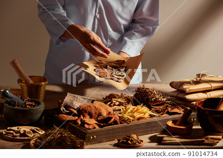 Traditional chinese medicine with herb and spices in brown wooden background mortar and pestile  , doctor holding a pack of medicine for advertising ,  traditional content  91014734