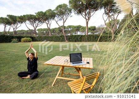 Girl meditating and practicing yoga on green lawn Girl meditating and practicing yoga on green lawn 91015141