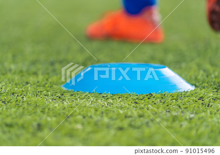 Sport Cone Marker for soccer training on a artifact field closed up shot Sport Cone Marker for soccer training on a artifact field closed up shot 91015496