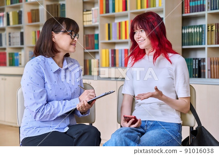 Psychologist, college counselor counseling teenage student in library, office Psychologist, college counselor counseling teenage student in library, office 91016038
