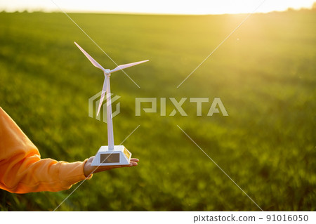 Person holds toy wind generator on field 91016050