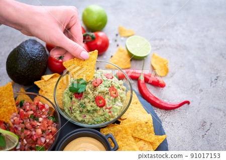 freshly made salsa and guacamole dip sauce with nacho chips on stone serving board freshly made salsa and guacamole dip sauce with nacho chips on stone serving board 91017153
