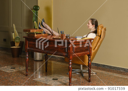 A woman threw her legs on the table at work 91017339