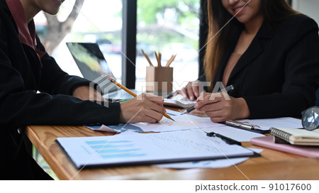 Cropped shot two business colleagues analyzing financial graph and summarize the data together at office desk Cropped shot two business colleagues analyzing financial graph and summarize the data together at office desk 91017600