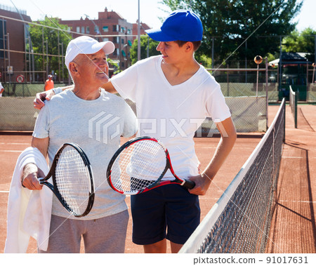 grandfather and grandson talking on court playing tennis 91017631