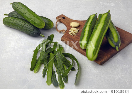 Fresh cucumbers with skin and peeled on a brown wooden cutting board 91018984