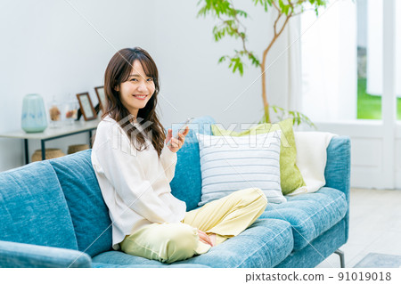 Young woman looking at her smartphone in the living room Young woman looking at her smartphone in the living room 91019018