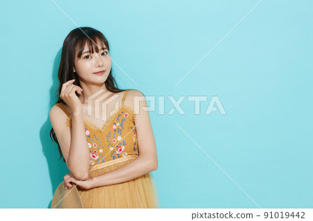Blue background portrait of a young woman in resort fashion Blue background portrait of a young woman in resort fashion 91019442