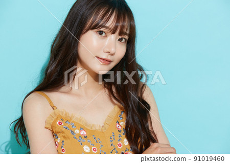 Blue background portrait of a young woman in resort fashion Blue background portrait of a young woman in resort fashion 91019460