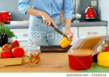 Young blonde caucasian woman cutting vegetables for salad at her kitchen Young blonde caucasian woman cutting vegetables for salad at her kitchen 91020216